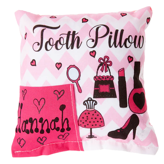 Decorative pillow with 'Tooth Pillow Hannah' text and fashion-themed illustrations on a pink and white chevron background.
