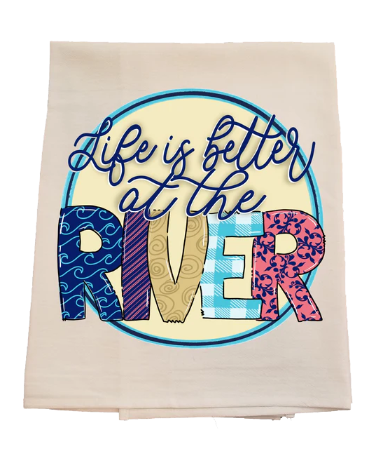 Towel with 'Life is better at the river' text and colorful letters on a white background