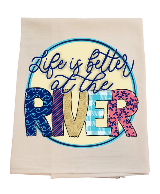 Towel with 'Life is better at the river' text and colorful letters on a white background