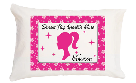 Decorative pillow with pink silhouette of a girl, text 'Dream Big Sparkle More' and name 'Emerson' on a white background.