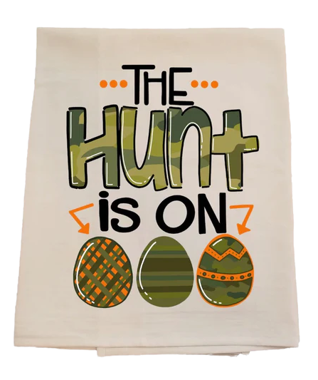 Beige towel with 'The Hunt is On' text and Easter egg designs on a white background